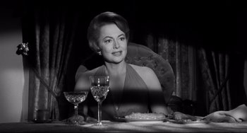 Movie still from “Hush...Hush, Sweet Charlotte” (1964), directed by Robert Aldrich – A woman sitting at a table with a glass of wine in front of her; Medium shot, Low angle