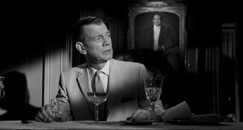 Movie still from “Hush...Hush, Sweet Charlotte” (1964), directed by Robert Aldrich – A man sitting at a table with a glass of wine in front of him; Medium shot, Over the shoulder angle