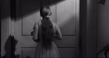 Movie still from “Hush...Hush, Sweet Charlotte” (1964), directed by Robert Aldrich – A woman standing in front of a door with her hair in a ponytail; Medium shot, Over the shoulder angle