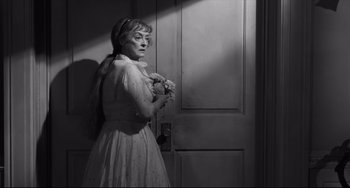 Movie still from “Hush...Hush, Sweet Charlotte” (1964), directed by Robert Aldrich – An older woman holding flowers in front of an open door; Medium shot, High angle