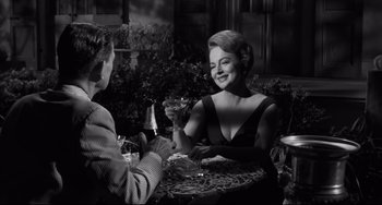 Movie still from “Hush...Hush, Sweet Charlotte” (1964), directed by Robert Aldrich – A woman sitting at a table holding a wine glass; Medium shot, Over the shoulder angle