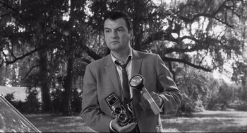 Movie still from “Hush...Hush, Sweet Charlotte” (1964), directed by Robert Aldrich – A black and white photo of a man holding a camera; Close Up shot, Low angle