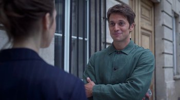 Movie still from “Emily in Paris” (2020), created by Darren Star – A man in a green jacket talking to a woman; Medium shot, Over the shoulder angle
