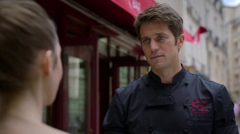 Movie still from “Emily in Paris” (2020), created by Darren Star – A man wearing a black chef's outfit looking at a woman; Close Up shot, Over the shoulder angle
