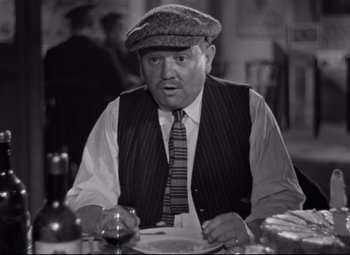 Movie still from “Hotel du Nord” (1938), directed by Marcel Carné – An older man sitting at a table with a plate; Medium shot, Low angle
