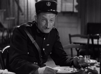 Movie still from “Hotel du Nord” (1938), directed by Marcel Carné – A man in uniform sitting at a dining table; Medium shot, High angle