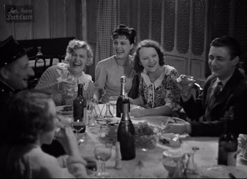 Movie still from “Hotel du Nord” (1938), directed by Marcel Carné – A group of people sitting around a table with wine glasses; Medium shot, High angle