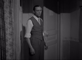 Movie still from “Hotel du Nord” (1938), directed by Marcel Carné – A black and white photo of a man standing in front of a door; Medium shot, High angle