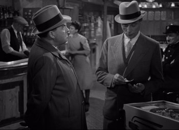 Movie still from “Hotel du Nord” (1938), directed by Marcel Carné – Two men in suits and hats talking to each other in a store; Medium shot, High angle