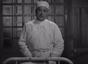 Movie still from “Hotel du Nord” (1938), directed by Marcel Carné – A man wearing a white hat standing in front of a bed; Medium shot, Low angle
