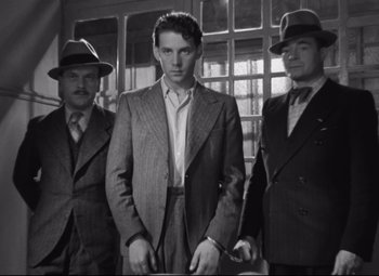 Movie still from “Hotel du Nord” (1938), directed by Marcel Carné – A man standing next to two other men in suits; Medium shot, Low angle