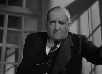 Movie still from “Hotel du Nord” (1938), directed by Marcel Carné – An older man wearing a suit and tie; Close Up shot, High angle