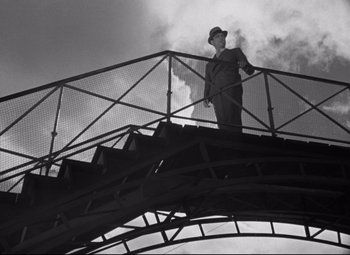 Movie still from “Hotel du Nord” (1938), directed by Marcel Carné – A black and white photo of a man standing on top of a bridge; Wide shot, Low angle