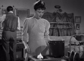 Movie still from “Hotel du Nord” (1938), directed by Marcel Carné – A black and white photo of a woman cooking; Medium shot, High angle