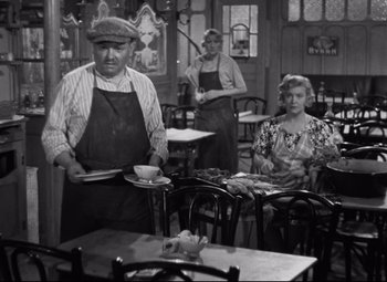 Movie still from “Hotel du Nord” (1938), directed by Marcel Carné – An old photo of a man and two women sitting at a table; Medium shot, High angle
