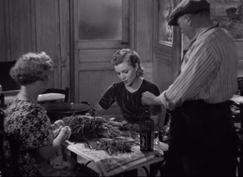 Movie still from “Hotel du Nord” (1938), directed by Marcel Carné – An old photo of a woman and two men at a table; Medium shot, High angle