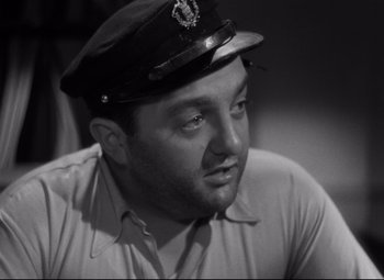 Movie still from “Hotel du Nord” (1938), directed by Marcel Carné – A man wearing a hat sitting in a room; Close Up shot, Low angle