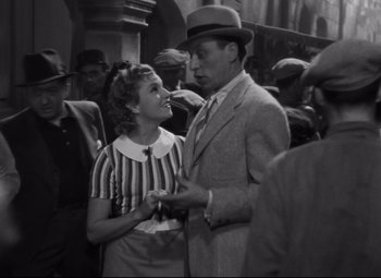 Movie still from “Hotel du Nord” (1938), directed by Marcel Carné – A man and a woman standing next to each other in a crowd; Medium shot, Over the shoulder angle