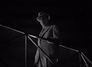 Movie still from “Hotel du Nord” (1938), directed by Marcel Carné – A black and white photo of a man in a suit and hat; Medium shot, Low angle