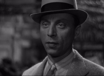 Movie still from “Hotel du Nord” (1938), directed by Marcel Carné – A black and white photo of a man wearing a hat; Close Up shot, High angle