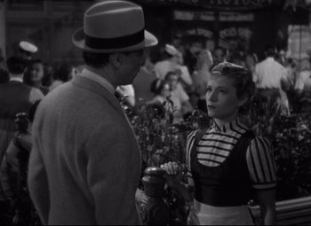 Movie still from “Hotel du Nord” (1938), directed by Marcel Carné – A man and a woman are standing in front of a crowd of onlookers; Medium shot, Over the shoulder angle