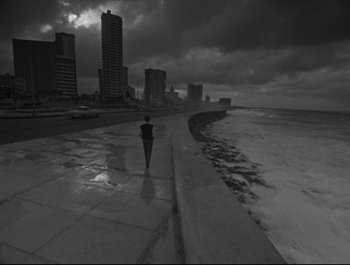 A person walking on a sidewalk near the ocean
