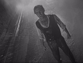 A black and white photo of a man walking in the rain