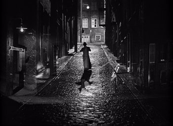 Movie still from “I Confess” (1953), directed by Alfred Hitchcock – A person jumping in the air in the middle of a street; Extreme Wide shot, High angle