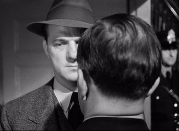 Movie still from “I Confess” (1953), directed by Alfred Hitchcock – A black and white photo of a man in a hat looking at himself in the mirror; Close Up shot, Over the shoulder angle