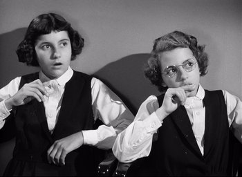 Movie still from “I Confess” (1953), directed by Alfred Hitchcock – Two young women are posing for a picture; Medium shot, High angle