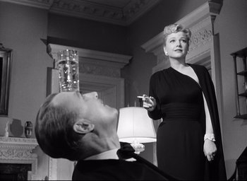 Movie still from “I Confess” (1953), directed by Alfred Hitchcock – An old photo of a man and a woman smoking; Medium shot, Low angle