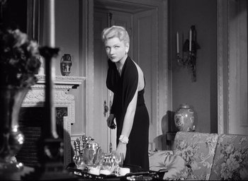 Movie still from “I Confess” (1953), directed by Alfred Hitchcock – An old photo of a woman standing in a living room; Medium shot, Low angle