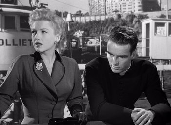 Movie still from “I Confess” (1953), directed by Alfred Hitchcock – A man and a woman sitting next to each other; Medium shot, Low angle