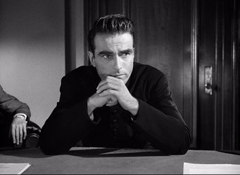 Movie still from “I Confess” (1953), directed by Alfred Hitchcock – Black and white photograph of a man sitting at a table; Close Up shot, Low angle