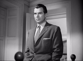 Movie still from “I Confess” (1953), directed by Alfred Hitchcock – Black and white photograph of a man in a suit; Medium shot, Low angle