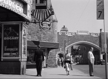 Movie still from “I Confess” (1953), directed by Alfred Hitchcock – A black and white photo of people walking down the street; Wide shot, Low angle