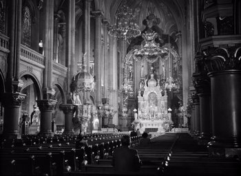 Movie still from “I Confess” (1953), directed by Alfred Hitchcock – A black and white photo of a church with pews; Extreme Wide shot, High angle