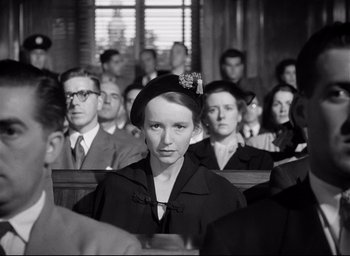 Movie still from “I Confess” (1953), directed by Alfred Hitchcock – An old photo of a woman in a crowd of people; Medium shot, Low angle