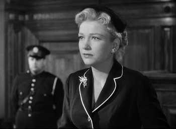 Movie still from “I Confess” (1953), directed by Alfred Hitchcock – An old photo of a woman in a black suit; Medium shot, Low angle