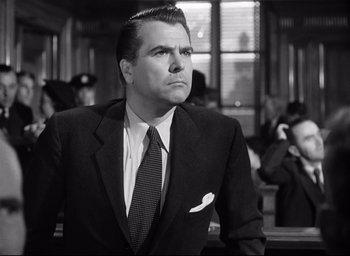 Movie still from “I Confess” (1953), directed by Alfred Hitchcock – Black and white photograph of a man wearing a suit and tie; Medium shot, Low angle