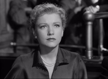 Movie still from “I Confess” (1953), directed by Alfred Hitchcock – An old photo of a woman in a black shirt and pearl necklace; Close Up shot, High angle