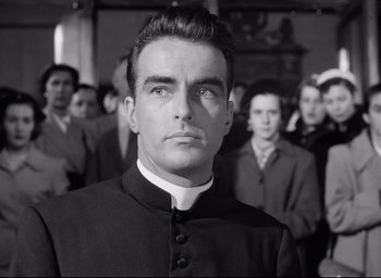 Movie still from “I Confess” (1953), directed by Alfred Hitchcock – Black and white photograph of a priest in front of a crowd; Close Up shot, Low angle