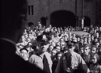 Movie still from “I Confess” (1953), directed by Alfred Hitchcock – Black and white photograph of a large group of people; Wide shot, High angle