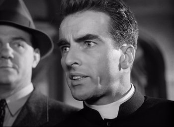 Movie still from “I Confess” (1953), directed by Alfred Hitchcock – Black and white photograph of a man in a clerical collar; Close Up shot, Low angle