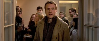 Movie still from “I Give It a Year” (2013), directed by Dan Mazer – A man standing in front of a group of people; Medium shot, Over the shoulder angle