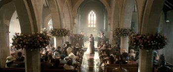 Movie still from “I Give It a Year” (2013), directed by Dan Mazer – A couple is kissing in a church with a lot of people; Extreme Wide shot, High angle