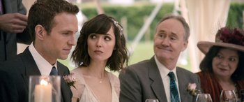 Movie still from “I Give It a Year” (2013), directed by Dan Mazer – A man and a woman sitting next to each other at an event; Close Up shot, Over the shoulder angle