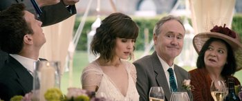 Movie still from “I Give It a Year” (2013), directed by Dan Mazer – A woman in a white dress is sitting at a table with an older man; Close Up shot, Over the shoulder angle