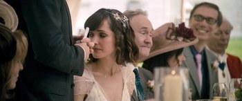 Movie still from “I Give It a Year” (2013), directed by Dan Mazer – A woman in a white dress holding her hand up to her ear; Close Up shot, Over the shoulder angle