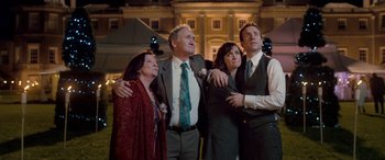 Movie still from “I Give It a Year” (2013), directed by Dan Mazer – A group of people standing next to each other in front of a building; Medium shot, Low angle